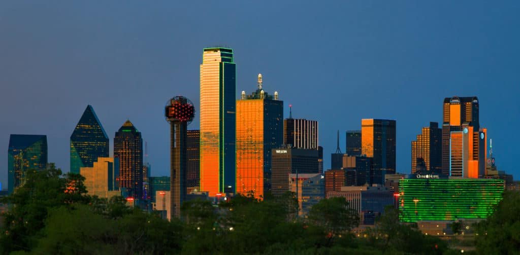 The Dallas skyline is lit up at dusk, providing a stunning backdrop for a limousine ride or airport transfer.