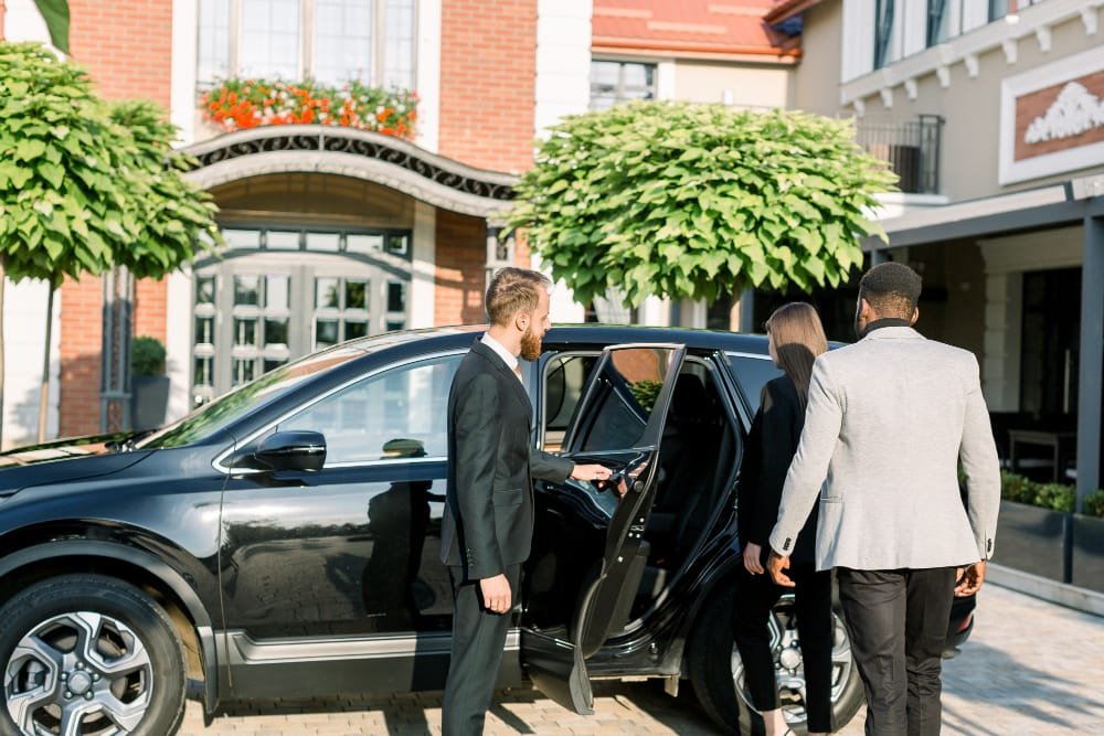 A group of business people exiting a black limousine.