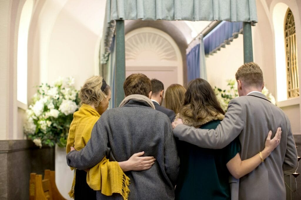A group of people hugging in a church, celebrating a joyful reunion after their airport transfer.
